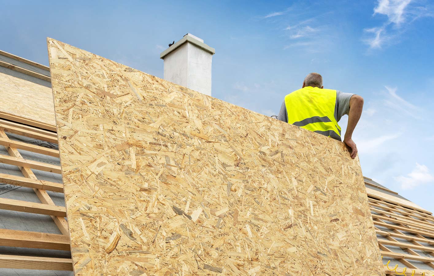 große OSB-Platte mit einem Handwerker dahinter