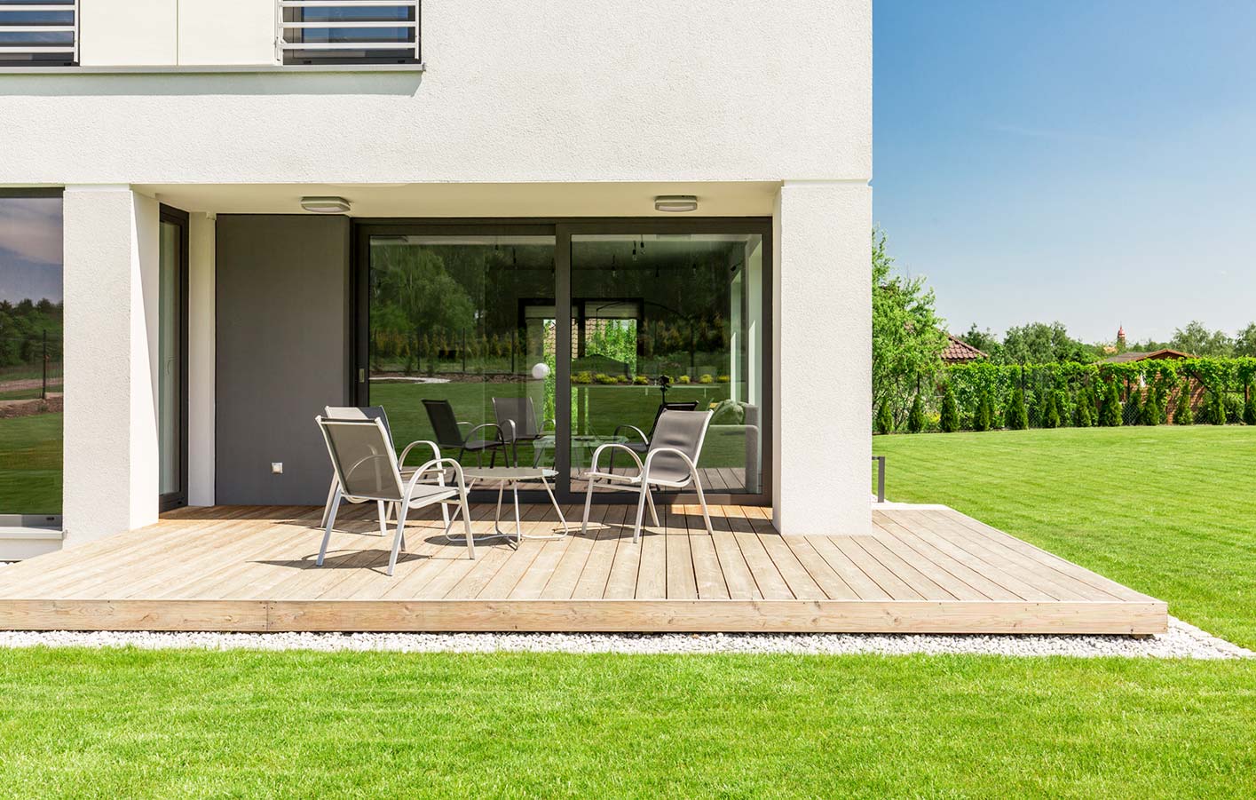 Holzterrasse mit Terrassenmöbeln in einem modernen Garten