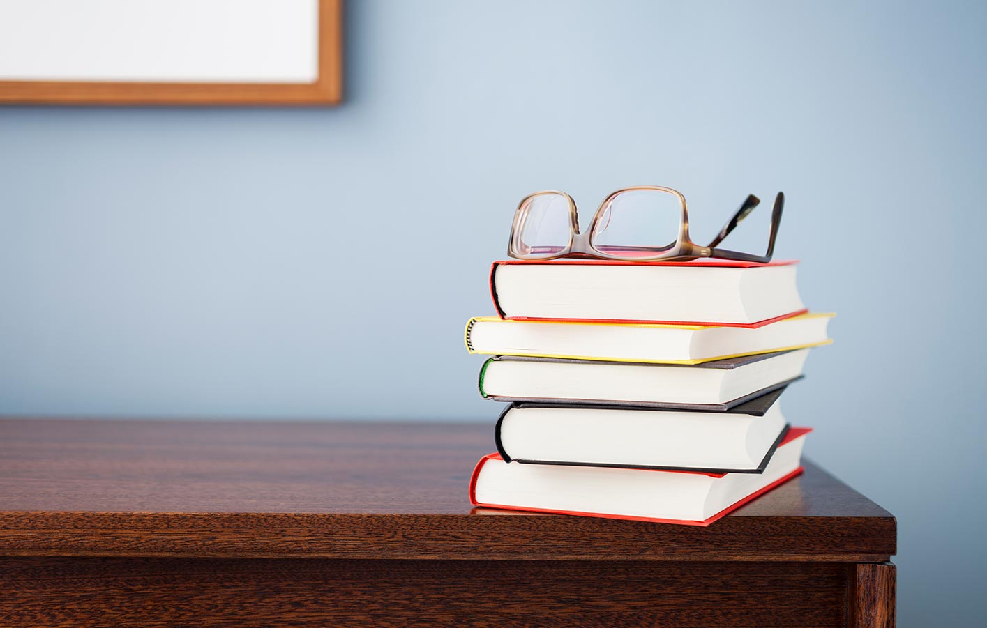 Bücherstapel auf einem Regal mit einer Brille oben drauf